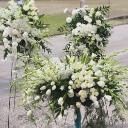 Large white floral funeral sprays with roses and lilies on stands