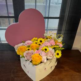 Heart-shaped box of pink and yellow flowers