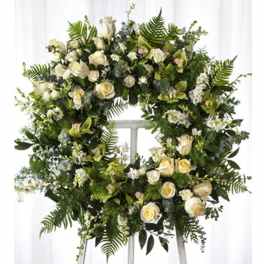 Large white floral wreath with roses and greenery on an easel