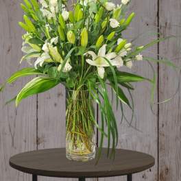Tall white floral arrangement in a clear glass vase