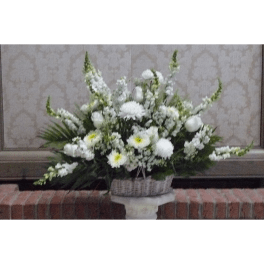 White floral arrangement in a woven basket on a pedestal