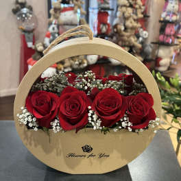 Red roses arranged in a round cardboard gift box with baby's breath