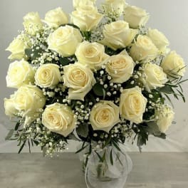 Bouquet of cream roses with baby's breath in a clear glass vase