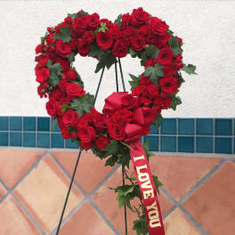 Heart-shaped red rose wreath with a ribbon that says I LOVE YOU