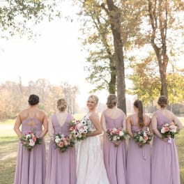 Bride and bridesmaids holding pastel bouquets outdoors