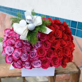 Heart-shaped bouquet of red and pink roses with a white ribbon bow