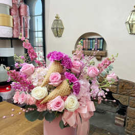 Pink and white rose arrangement in a pink hatbox with waffle cones