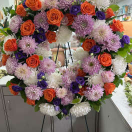 Heart-shaped floral wreath with orange roses, purple blooms, and white chrysanthemums