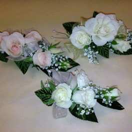 Three rose boutonnieres in pink and white with baby's breath