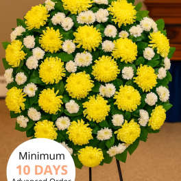 Round standing spray of yellow and white chrysanthemums on a metal easel