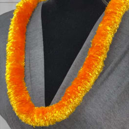 Orange and yellow fluffy lei necklace displayed on a gray-draped black mannequin.