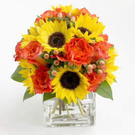 Sunflowers and orange roses in a clear glass vase