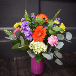 Colorful mixed bouquet in a magenta vase with gerbera daisies and hydrangea