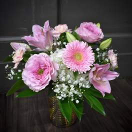 Pink lilies and gerbera daisies arranged in a glass vase