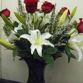 Bouquet of red roses and white lilies in a dark vase