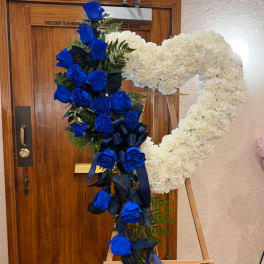 Blue rose and white carnation heart-shaped funeral wreath on an easel