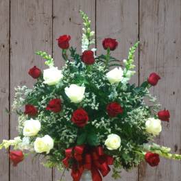 Red and white roses arranged in a vase with a red ribbon