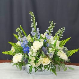 White and blue floral arrangement in a low container