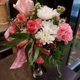 Pink and white mixed bouquet in a clear glass vase with a pink ribbon