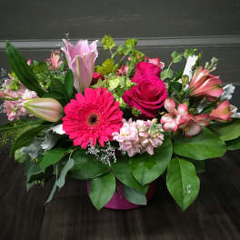 Mixed pink floral arrangement in a round pink container