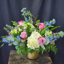 Pink roses and white hydrangea in a gold vase with blue flowers