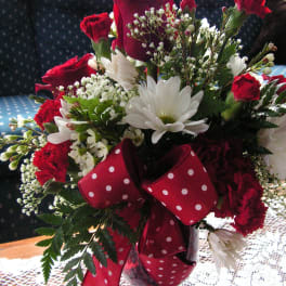 Bouquet of red roses, white daisies, and carnations with a red polka-dot ribbon