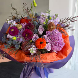 Bouquet of purple and pink flowers wrapped in orange and purple paper