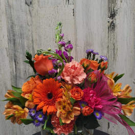Bright mixed bouquet in a glass vase with orange, pink, and purple flowers