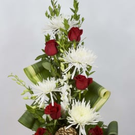 Red roses and white spider mums in a red vase with green leaf wrap