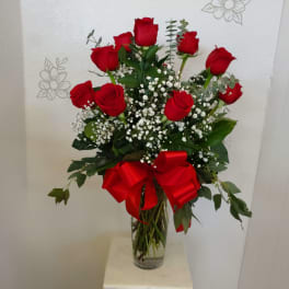 Red roses in a clear glass vase with a red ribbon