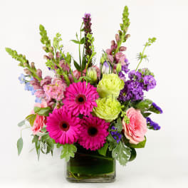 Bright mixed bouquet in a clear glass vase with pink and purple blooms