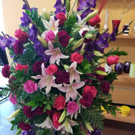 Large standing arrangement of pink roses, lilies, and purple flowers