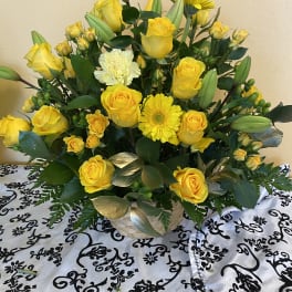 Yellow roses and a yellow gerbera daisy in a basket arrangement