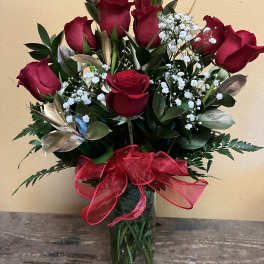 Red roses arranged in a clear glass vase with a red ribbon