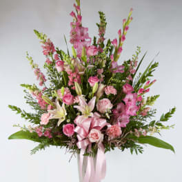Tall pink floral arrangement in a vase with a pink ribbon bow
