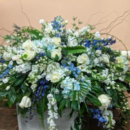 Large white and blue floral arrangement in a rectangular container