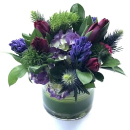 Purple and burgundy floral arrangement in a glass vase