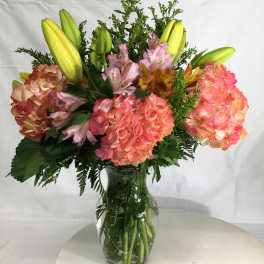Bouquet of pink hydrangeas and yellow lilies in a glass vase