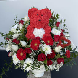 Heart-shaped teddy bear made of red roses in a mixed floral arrangement