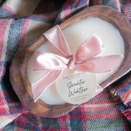 White oval candle in a wooden tray with a pink ribbon