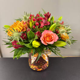 Mixed bouquet in a decorated vase with orange and red blooms