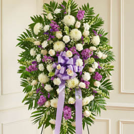 Standing funeral spray of white and purple flowers with a lavender ribbon