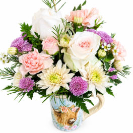 Bouquet of pink, white, and purple flowers in a decorative mug vase