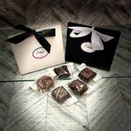 Two ribbon-tied gift boxes with wrapped chocolates on the floor