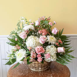 Pink and white mixed flower arrangement in a wicker basket