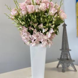 Pink roses and small pale pink flowers in a tall white vase