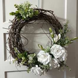 White floral wreath on a grapevine ring with green accents