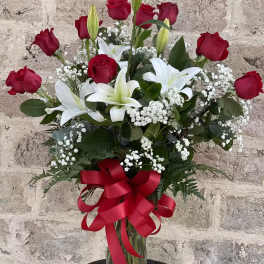 Red roses and white lilies in a glass vase with a red ribbon