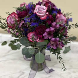 Bouquet of pink roses and purple flowers in a glass vase