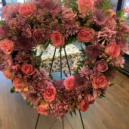Heart-shaped floral wreath with pink and purple roses on a stand